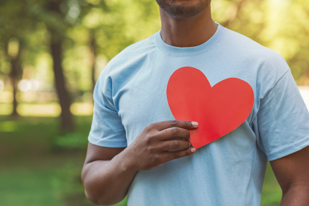 Closeup of a man holding a big read heart close to his heart