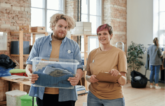 Two volunteers holding a box of clothes